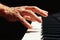 Hand of pianist play the keys of the digital piano on black background close up