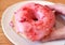 Hand picking a delectable doughnut with strawberry-glazed and raspberry cream filling