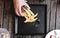 Hand picking last piece of sandwich, on square black dish, on wooden table