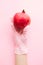 Hand in pink glove holding pomegranate on pink background flat lay. Order groceries and get them delivered safe during quarantine