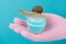 Hand in a pink glove holds a turquoise container for cosmetics, a snail sits on top, craning its neck, concept