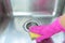 Hand in pink rubber glove clean stainless steel sink with sponge