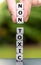 Hand places three dice on a stack and changes the word `toxic` to `non toxic