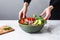 a hand placing a bowl of avocado salad on a marble table