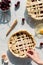 A hand placing decorative leaves on a fall themed cherry pie in bright sunlight.