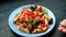 Hand Placing a Freshly Cooked Marinara Roasted Vegetables Penne on Table and Garnishes with Basil Leaves
