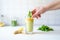 hand placing ginger slice into green detox smoothie glass