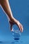 Hand placing a glass of water on blue surface