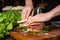 hand placing lettuce on a generous pile of deli meat on bread