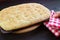 Hand Placing a Pan of Freshly Baked Focaccia Bread on the Breadboard