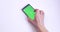 Hand Placing Smart Phone With Green Chroma Screen On White Table Closeup