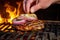hand placing thick slice of onion onto flame grilled burger