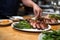 hand plating grilled duck with asparagus on the side