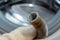 Hand of a plumber holding a broken flexible drain hose of washing machine, clogged and covered with lime scale, dirt limescale and