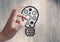 Hand pointing at cogs in lightbulb graphic and flare against grey wood panel