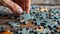 Hand poised to place a teal puzzle piece onto an unfinished jigsaw puzzle