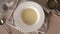 Hand pouring homemade bone broth into a white plate with a ladle, top view