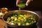 hand pouring oil into pan for saag aloo