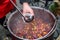 Hand pours mulled wine from bowl into glass