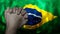 A hand praying with Flag of Brazil as background. Grunge, depressing look.