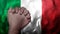 A hand praying with Flag of Italy as background. Grunge, depressing look.