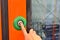 The hand presses the button for stop in the train. Orange door of train carriage with the electric blue button press to open