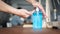 The hand that is pressing the blue clear gel bottle is placed on the table with a blurred