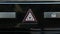 Hand pressing the emergency triangle of the dashboard of a car