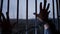 Hand of prisoner in chains against prison bars