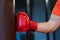 Hand of professional athlete muscular man boxer in red gloves in front of punching bag