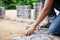 Hand of professional paver worker lays paving stones in layers for pathway