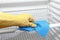 Hand with protective glove cleaning refrigerator