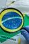 Hand in a protective glove holding a magnifying glass over the flag of Brazil, Coronavirus tubes, anti-virus masks. The concept of