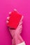 Hand in protective glove holding red sponge