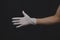 Hand in protective glove reach out. gesturing hand in white medical glove on a black background
