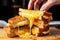 hand pulling apart grilled cheese sandwich showing gooey cheese