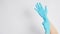 Hand is pulling blue latex gloves on white background