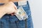 a hand pulls dollar bills out of the pocket of someone else\'s jeans. The concept of theft