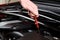 Hand pulls out oil dipstick in a clean car engine bay