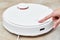 Hand push start button on robot vacuum cleaner. Modern smart household