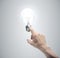 Hand pushing light bulb on gray background