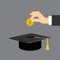 Hand put gold coin in graduation cap.