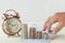 Hand put money on pile of coins with clock and book bank