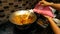 Hand put some coconut milk into the fish head curry in the metal wok to make the food more tasty