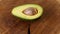 Hand puts the green avocado to the white table and spin the fruit, closeup
