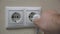 Hand puts a power plug in the dirty, unclean wall socket