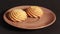 A hand puts shortbread cookies on a brown saucer.