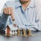 Hand putting coin in house model of coin for saving money for buying house. Savings plans for home, loan, investment, mortgage,