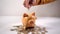 A hand is putting coin in a pig bank on a pile of coins and on white background. saving money is an investment for the future