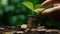 Hand putting coins with plant growing on coin stack over green blurred background. Business finance strategy, money